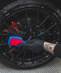 Person cleaning black wheel with ProGrip Wheel Face Brush With Ergonomic Rubberized Handle Pro Grade Wheel Cleaner Brush.