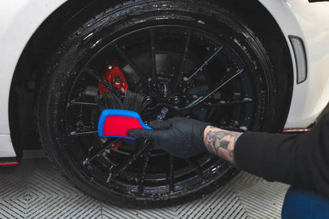 Person cleaning black wheel with ProGrip Wheel Face Brush With Ergonomic Rubberized Handle Pro Grade Wheel Cleaner Brush.
