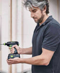 Person using Centrotec BH 60 Impact Bit Holder with Magnetic Retention, attached to a drill, in a construction setting.