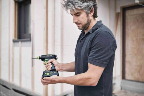 Person using Centrotec BH 60 Impact Bit Holder with Magnetic Retention, attached to a drill, in a construction setting.