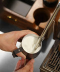 12 Oz Stainless Steel Milk Frothing Pitcher For Espresso And Latte Art Black Round Spout Milk Jug being used on espresso machine.