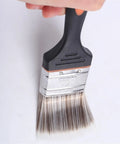 Hand holding versatile paint brush set for DIY projects and home improvement includes 2 inch wide brushes for stains varnishes