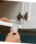 Silver soft-close inset cabinet hinge with mounting plate being installed on a white cabinet door