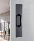 Commercial 15 Inch Stainless Steel Pull Door Plate In Matte Black Finish mounted on a door, pre-drilled for industrial duty entrances.