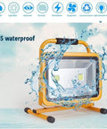 Heavy Duty 100W Rechargeable LED Floodlight With 270 Degree Swivel Bracket And Solid Aluminum Construction Waterproof Ip65 Rated, splashes of water over a yellow floodlight.