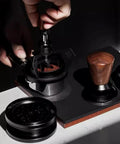 58mm Espresso Needle Distributor Features Nine Fine Thin Needles Adjustable Height Frame And Sleek Black Cleaning Base in use over coffee grounds.