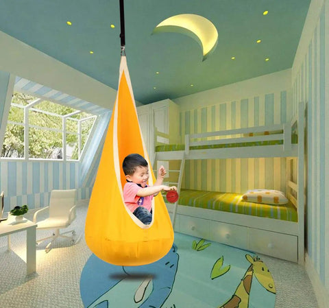 Child playing in Kids Pod Swing Hanging Seat For Indoor And Outdoor Use, Kid Friendly Hammock Chair with 100 Percent Cotton Mat and Cushion, Sensory Swing for Reading and Relaxing, Cozy Hangout That Supports Up To 170 Lbs, Bright Yellow in colorful playroom.