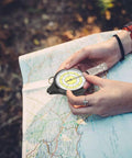 Wicked Compact Map Measure Wheel And Ridiculously Light Distance Calculator For Hiking Camping Trekking Trail Running And Road Trips Sleek Navigation Gear held above a map.