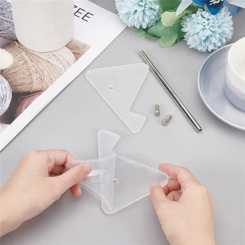Hands assembling Clear Acrylic Keyboard Stand 1 Tier Desk Holder components on a grey surface with decorative items nearby.