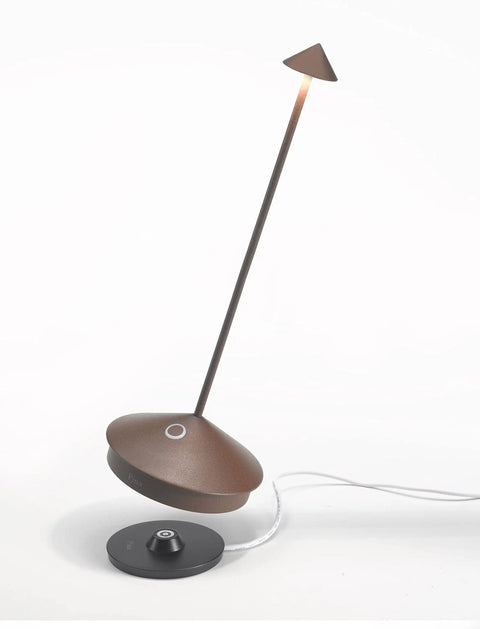 Pina Pro Cordless LED Table Lamp Rust Finish With Touch Dimming resting on contact charging base, shown from side angle