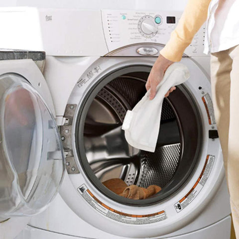 Front-loading washing machine with open door; hand holding a white cleaning cloth