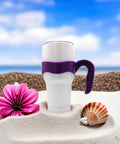 White mug with purple 30 Oz Tumbler Handle With Anti Slip Grip For Vacuum Insulated Mugs on beach sand with flower and shell