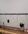 Heavy Duty Floating Shelf Brackets Fifty Eight Inches Long Invisible Mantel Supports For Thick Lumber Boards Matte Black Alloy Wall Mount Holders mounted on a wall above a countertop.