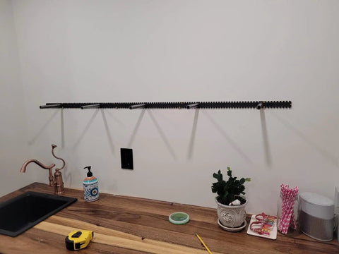 Heavy Duty Floating Shelf Brackets Fifty Eight Inches Long Invisible Mantel Supports For Thick Lumber Boards Matte Black Alloy Wall Mount Holders mounted on a wall above a countertop.