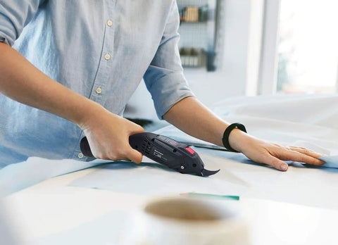 User operating Rechargeable Electric Scissors With Dual Lithium Battery Packs And Razor Sharp Blades on fabric.