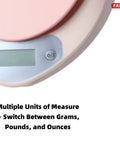 Close-up of digital kitchen scale with LCD display in pink finish, showing tare button and measurement units