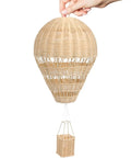 Hand holding rattan woven hot air balloon wall decor for kids room, cozy boho style, sturdy handmade craft nursery ornament.