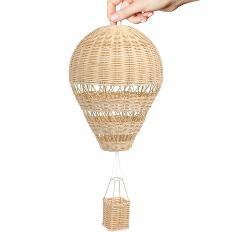 Hand holding rattan woven hot air balloon wall decor for kids room, cozy boho style, sturdy handmade craft nursery ornament.