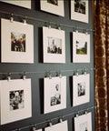 Photo display on wall using wire rope system with clips, showcasing black and white images in a modern setup.