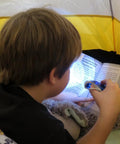 Child reading in tent with blue Hand Crank Emergency Flashlight Four Pack Rechargeable Crank Light With Dual LED
