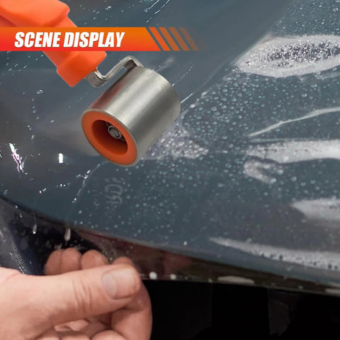 Car audio sound-deadening roller with orange handle and stainless steel wheel smoothing heat-insulation mats on a car panel
