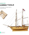 Wooden Mooring Tool For DIY Sailing Model Kits next to assembled wooden ship model, showcasing display use. Size: 7x5.5x0.7 cm.