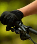 Gloved hand gripping Deore M6100 Front Hydraulic Brake Lever Aluminum Construction on mountain bike handlebar