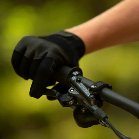 Gloved hand gripping Deore M6100 Front Hydraulic Brake Lever Aluminum Construction on mountain bike handlebar