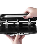 Hands using semi adjustable three hole punch for busy desks 30 sheet capacity black heavy duty paper punch for quick clean holes