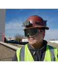 Worker wearing Tinted Safety Goggles With Anti Fog Lens For Pro Grade Eye Protection, Scratch Resistant UV Shield, hard hat and vest.