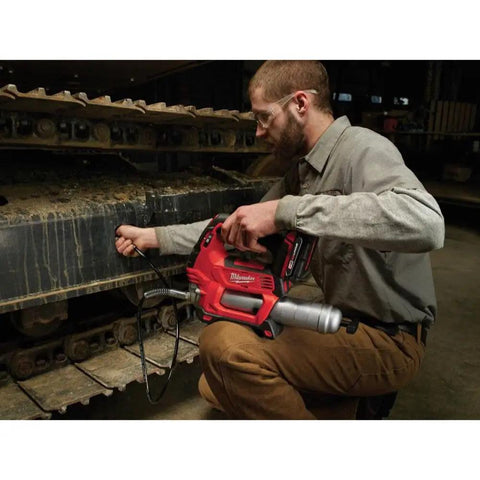 Man using M18 Cordless Grease Gun Kit With Chrome Finish on heavy machinery in workshop