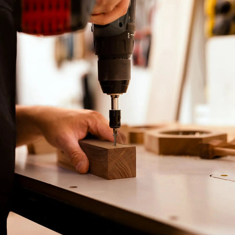User driving Tough As Nails 2 Inch Deck Screws Gauge 8 for outdoor wood fences into wood with a drill at a workbench.