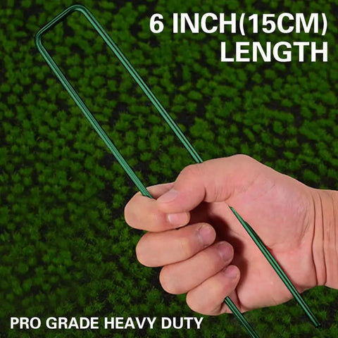 Hand holding Heavy Duty Green Landscape Staples 50 Pack 6 Inch Garden Stakes For Turf And Ground Fabric 11 Gauge Galvanized Lawn Pins Ideal For Weed Barrier Sod Fences Irrigation Tubing And Outdoor DIY Projects over a green background.
