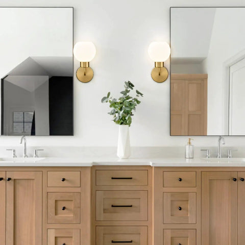 Gold Modern Bath Wall Sconce With Opal Glass Globe Vanity Lights Set Of 2 mounted above wood bathroom vanity with mirrors.