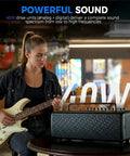 Person playing guitar next to 40W Desktop Amp For Acoustic Electric Bass And Mic With 52 Amp Models And 49 FX on table