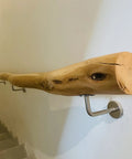 Built Like A Tank Adjustable Solid Wood Handrail Kit with sleek steel brackets mounted to a wall along a staircase.