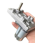 Badass 555 Size Dc Motor Paired With A Precision Steel Worm Gear Reducer 12 Volt And 24 Volt Drive Units held in hand.