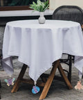 Outdoor table covered with white cloth, secured with Alloy Tablecloth Clips Eight Pack 2.36 Inch Wide Non Slip Holders, featuring insect pendants