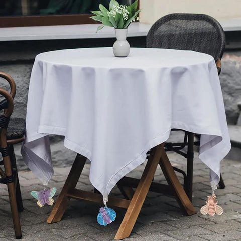 Outdoor table covered with white cloth, secured with Alloy Tablecloth Clips Eight Pack 2.36 Inch Wide Non Slip Holders, featuring insect pendants