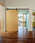 Barn Door Floor Guide Matte Black Metal Floor Mounted Bottom Guide Hardware Adjustable for Sliding Doors Two Pack Durable Carbon Steel With Powder Coated Finish Works With Grooved And Non Grooved Doors installed on a wooden sliding barn door in a modern living room.