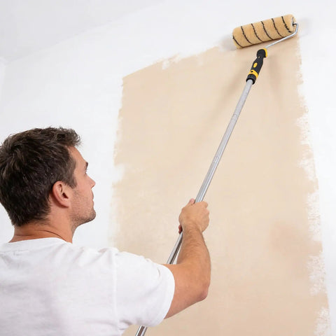 Man using 9 Inch Paint Roller Kit with Heavy Duty Stainless Steel Frame and Ultra Thick Nap for Ceilings and Walls on a beige wall.
