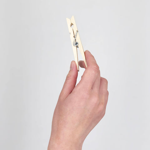 Tough As Nails Wooden Clothespins With Heavy Duty Spring Clip held in hand, showing natural wood finish and rust resistant design.