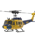 Yellow and blue remote control UH 1 C032 helicopter in flight with visible rotors and tail, front side view