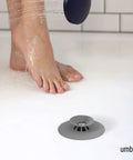 Dual Purpose Silicone Shower Drain Stopper And Hair Catcher Kills Sticky Pipe Buildup in use beside wet feet in shower.