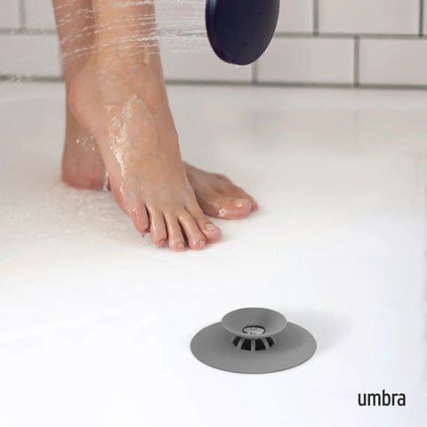 Dual Purpose Silicone Shower Drain Stopper And Hair Catcher Kills Sticky Pipe Buildup in use beside wet feet in shower.