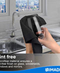 A hand cleaning a glass with a black microfiber towel from a Bulk 50 Pack Microfiber Cleaning Cloths 11.5 By 11.5 Inches Lint Free Reusable Towels.