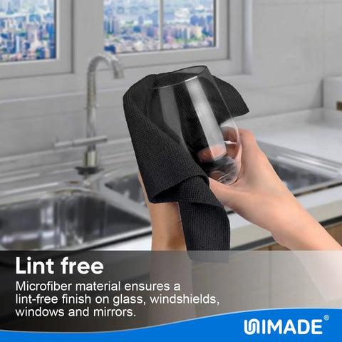 A hand cleaning a glass with a black microfiber towel from a Bulk 50 Pack Microfiber Cleaning Cloths 11.5 By 11.5 Inches Lint Free Reusable Towels.