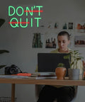 Motivational green LED neon sign 'DON'T QUIT' in a home office.