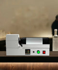 Electric PVC Wine Bottle Capsule Heat Shrinker, Tabletop Label Sealing Machine with digital display and wine bottle in use.