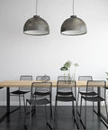 Modern dining room with black chairs, wooden table, and metal pendant lights, featuring White Peel And Stick Contact Paper on walls.